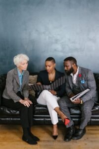 Three People Sitting on the Black Leather Couch